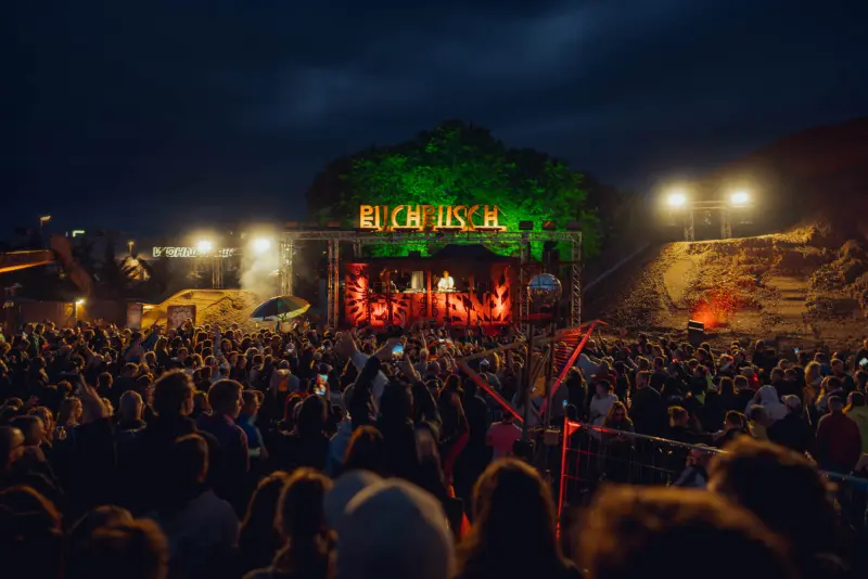 View over the crowd towards the lit Buchbusch stage at dusk
