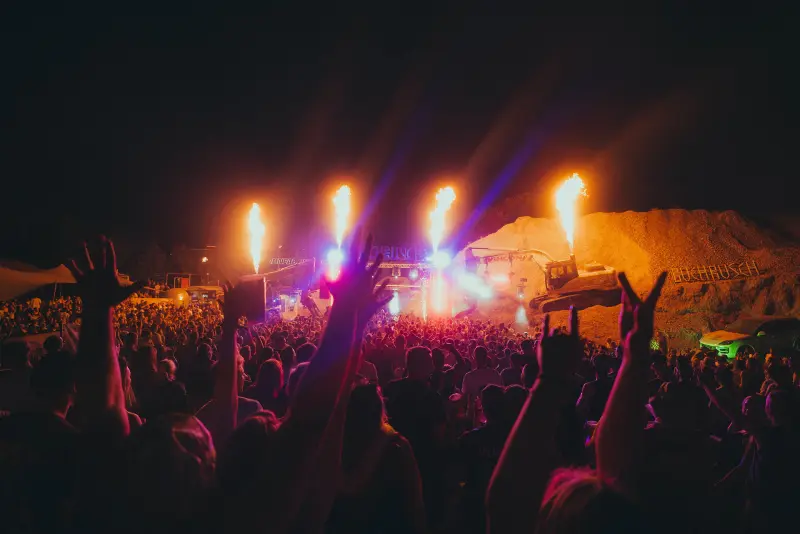 Raised hands in front of the stage with flames and coloured lights