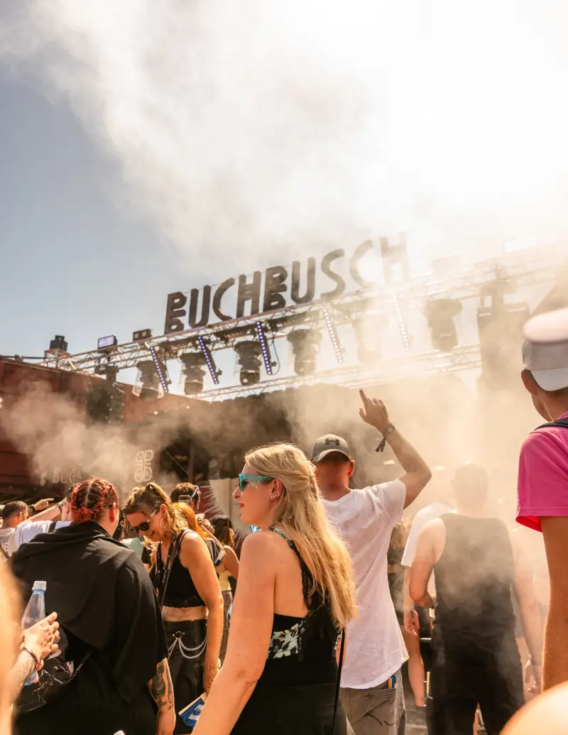 People dancing in the afternoon in front of the Buchbusch lettering in the stage haze